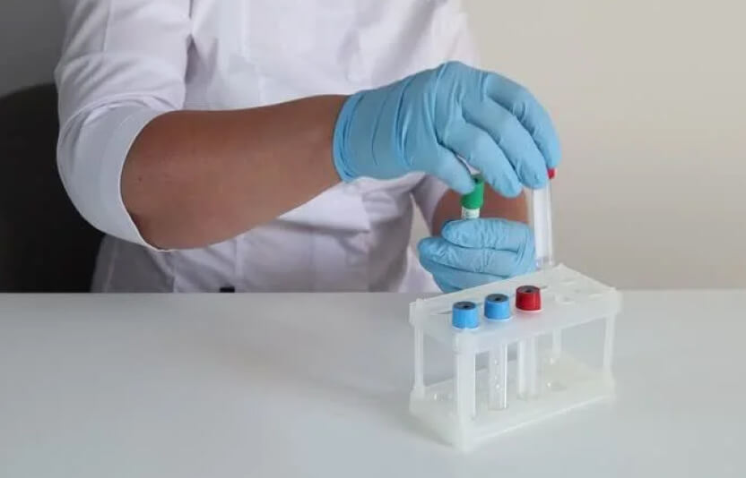 врач осматривает различные флакончики лекарств и пробирки у себя на столе